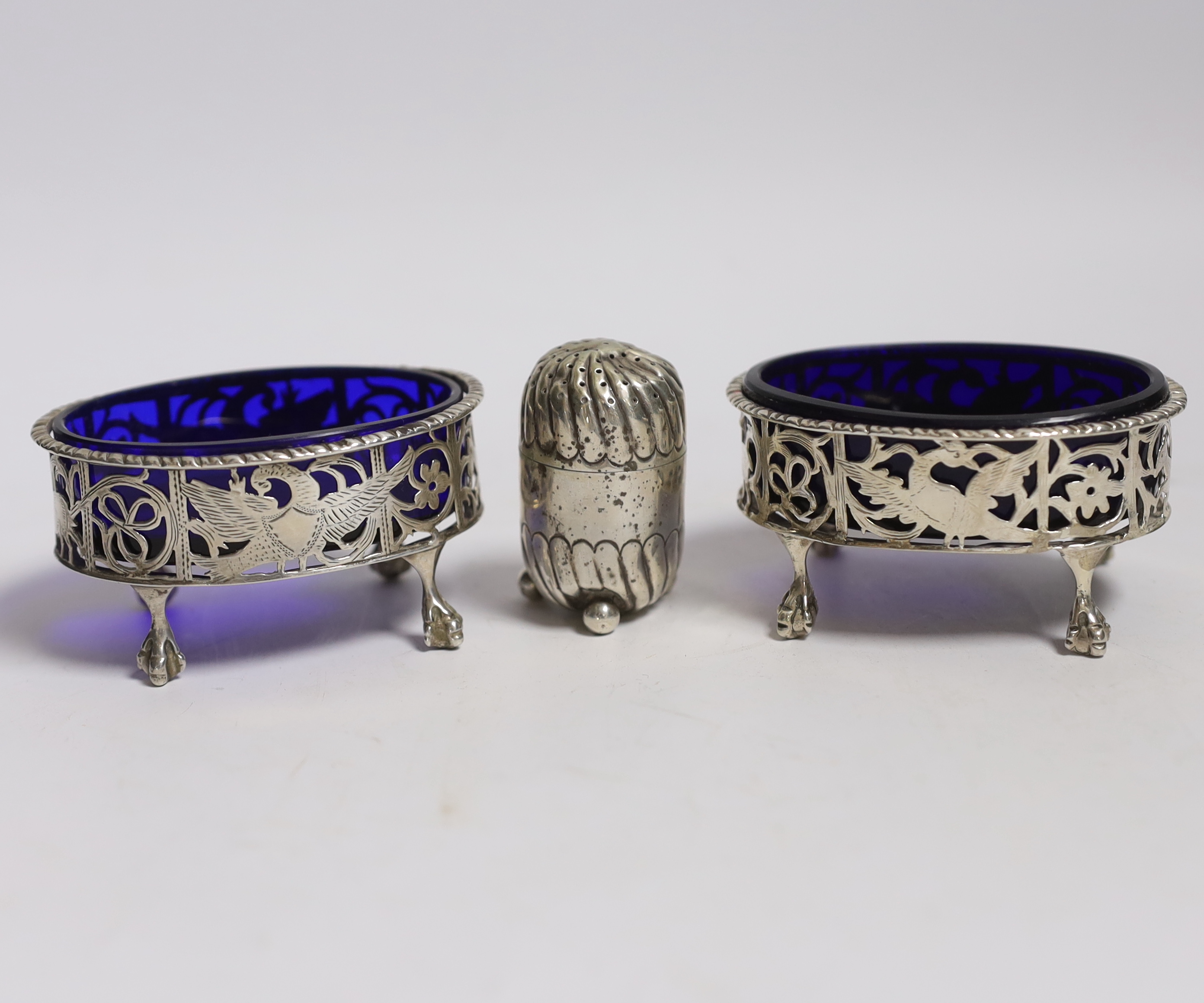 A pair of Edwardian pierced silver oval salts, Charles Stuart Harris, London, 1901/2, 82mm(a.f.), with blue glass liner and later associated spoons, together with a silver pepperette.